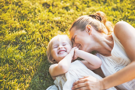Woman and kid lie on the grass laughing