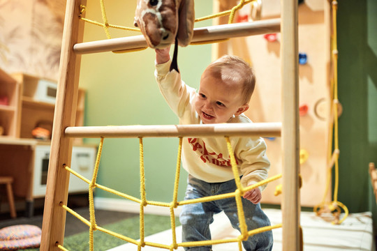 Kind spielt mit Spielzeug und Klettergerüst in der Kinderecke