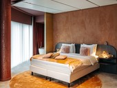 Doppelbett mit goldenen Kissen und dunkelgelbem Teppich